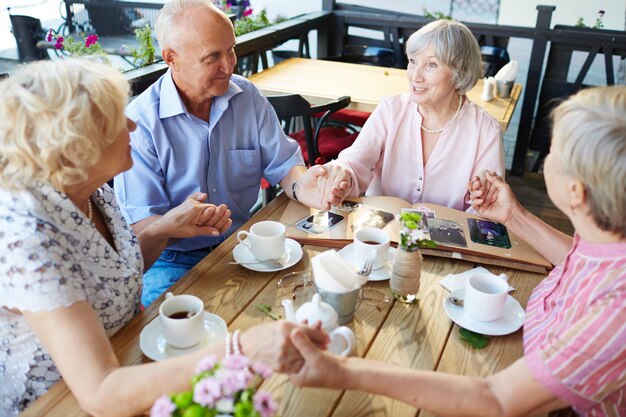 Senioren, die Hände im Café halten