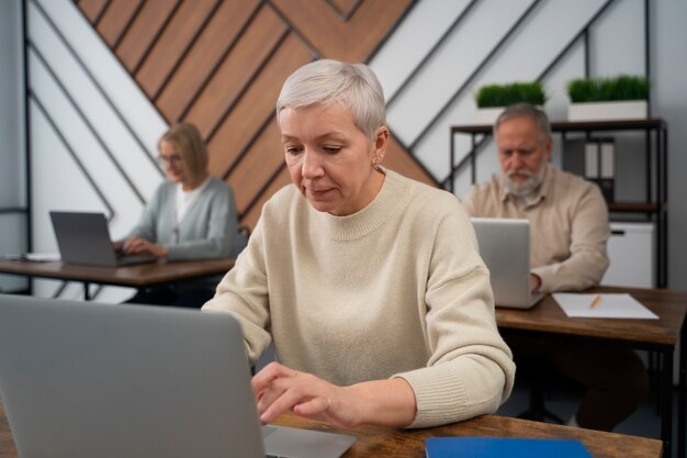 Senioren in der Schule während des Unterrichts mit Laptop-Computer