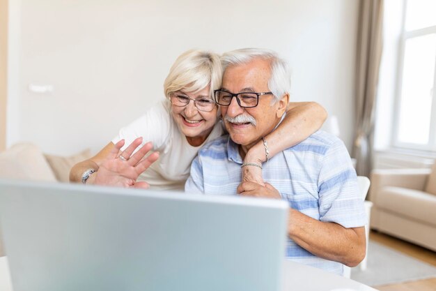 Seniorenpaar spricht online über Videoverbindung auf dem Laptop und hat eine schöne Zeit mit Freunden und Familie per Videoanruf