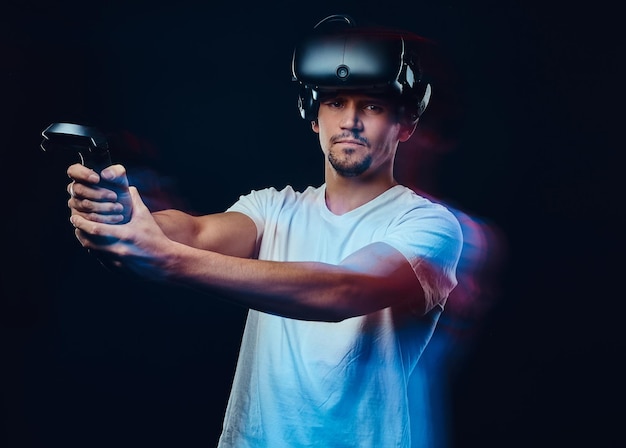 Kostenloses Foto seriöser profi-gamer in weißem hemd mit virtual-reality-brille und joysticks auf dunklem hintergrund. foto mit lichteffekt.
