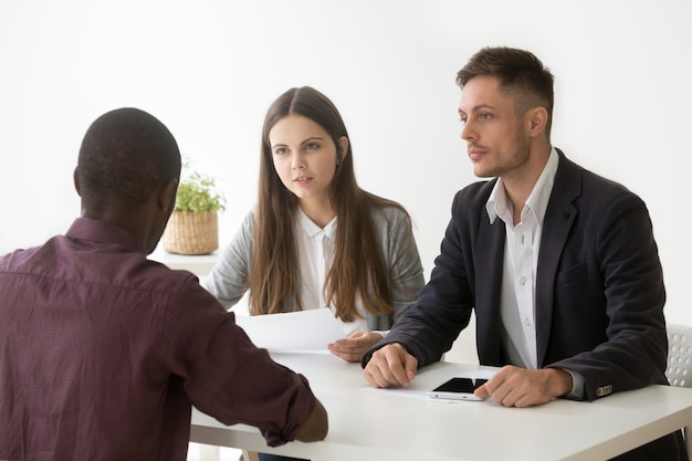 Kostenloses Foto serious hr-manager hören beim bewerbungsgespräch auf den afrikanischen bewerber