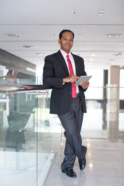 Serious indischen Geschäftsmann mit Touchpad in der Halle