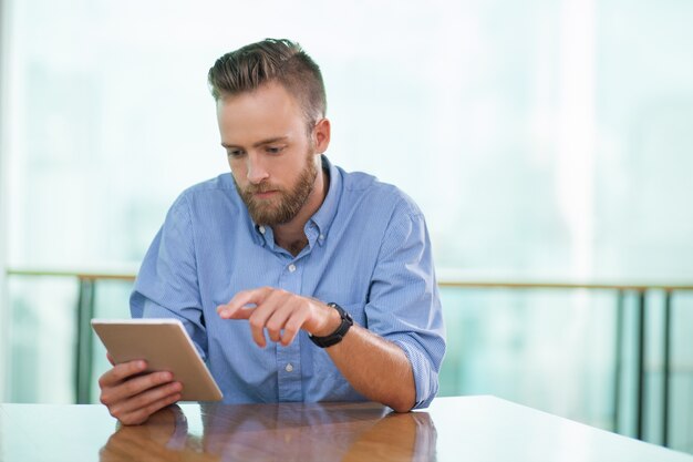 Serious Man sitzt am Tisch eines Cafes und Arbeiten mit dem Tablet