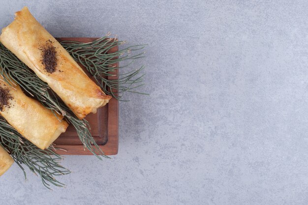 Servieren von russischen Blins auf einer Holzplatte, geschmückt mit Kiefernblättern auf Marmortisch.