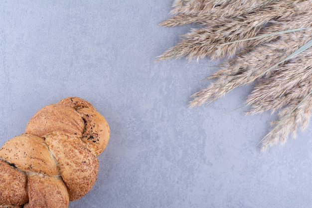 Sesambeschichtetes Strucia-Brot neben Stielen aus getrocknetem Federgras auf Marmoroberfläche