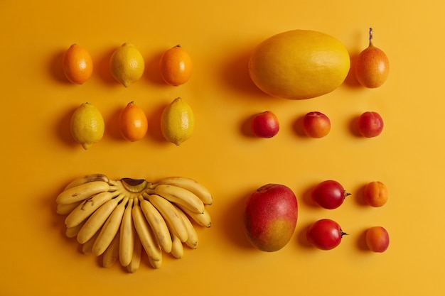 Set köstliche tropische Früchte zum Verzehr. Zitronen, Cumquat, Pfirsiche, Tamarillo, Bananen, Melone auf gelbem Grund. Nährstoffreiche Pflanzen, die reich an Vitaminen sind und als Zutaten für Obstsalat dienen