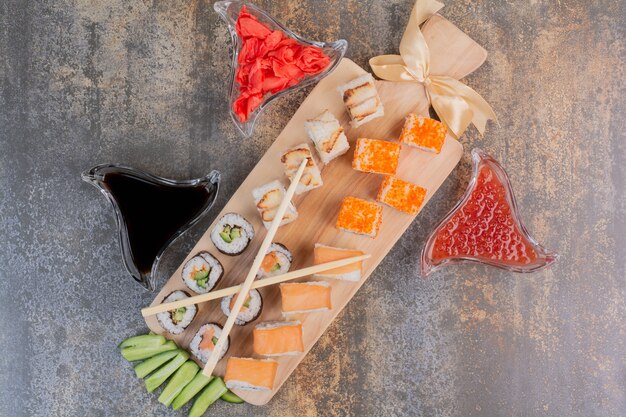 Set köstliches Sushi mit Stäbchen und Ingwer auf Marmorfläche