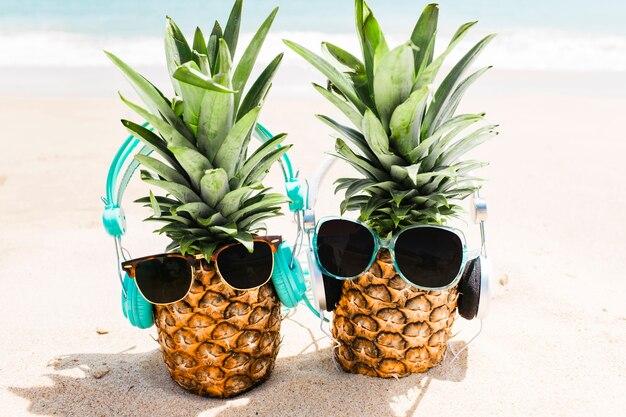 Setzen Sie Hintergrund mit den Ananas auf den Strand, die Kopfhörer und Sonnenbrille tragen