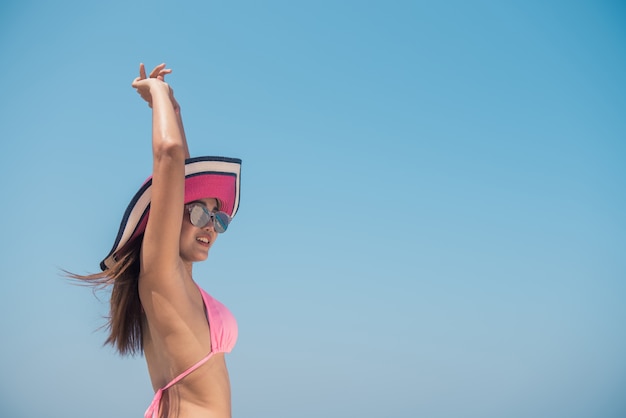 Sexy Bikini Körper asiatische Frau spielerisch auf Paradies tropischen Strand Spaß beim Spritzen Wasser in Freiheit mit offenen Armen. Schöne fit Körper Mädchen auf Reisen Urlaub. Banner-Ernte für Kopie Raum.