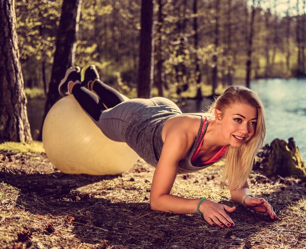 Sexy blonde Frau, die in einem Tagespark nach oben drückt.