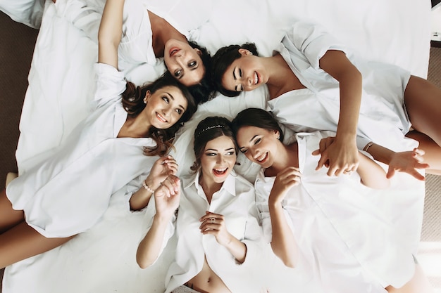 Sexy Braut &amp; Brautjungfern im Bett liegend vor der Hochzeit