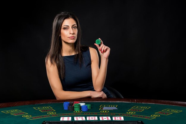 Sexy Frau mit Pokerkarten und Chips. Spielerin in einem schönen schwarzen Kleid