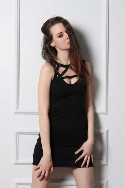 Kostenloses Foto sexy junge frau, die mit schwarzem kleid aufwirft