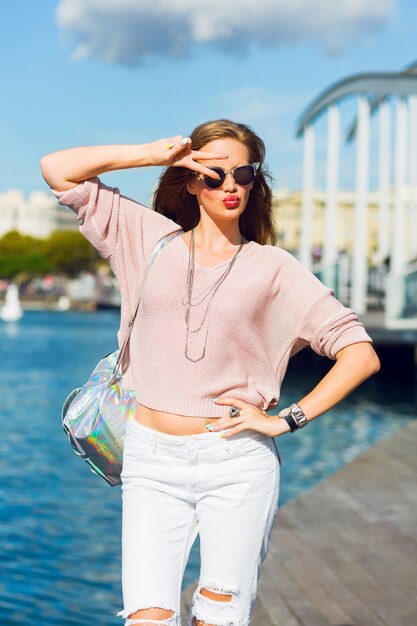 Sexy junge Frau in den weißen Kleidern, die im Garten am Meer aufwerfen. Mode Sommer Foto. Helle Farben, Sonnenbrille