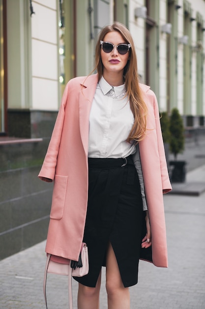 Sexy junge stilvolle schöne Frau, die in der Straße geht, rosa Mantel, Geldbörse, Sonnenbrille, weißes Hemd, schwarzen Rock, Mode-Outfit, Herbsttrend, glücklich lächelnd, Accessoires tragend