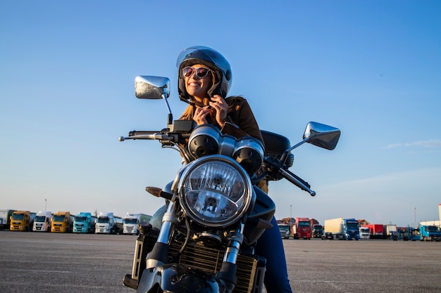 Sexy Mädchen, das auf Retro-Artmotorrad sitzt und Helmgürtel vor Fahrt festhält