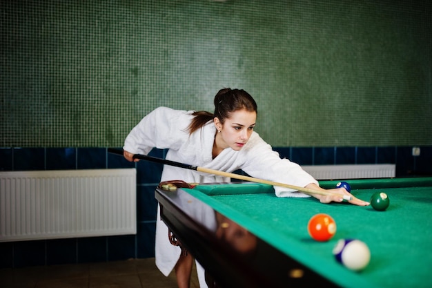 Sexy Mädchen im weißen Bademantel spielen Billard