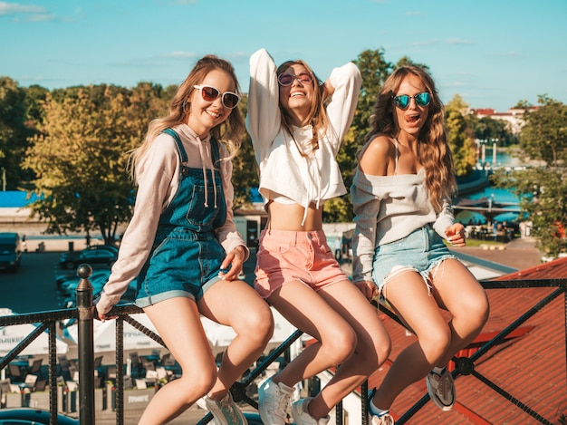 Sexy sorglose Frauen, die auf Geländer die Straße sitzen Positive Modelle, die Spaß in der Sonnenbrille haben