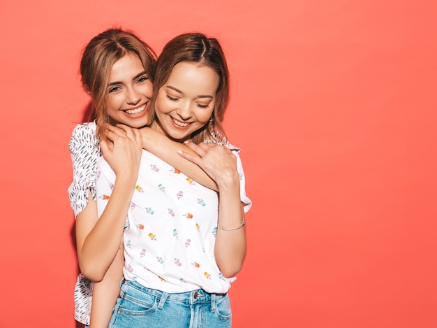 Sexy sorglose Frauen, die nahe blauer Wand aufwerfen. Positive Models, die Spaß haben