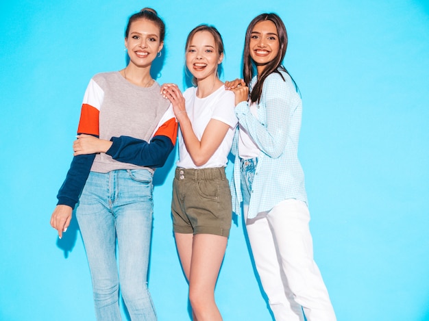 Sexy sorglose Frauen, die nahe blauer Wand im Studio aufwerfen. Positive Models, die Spaß haben und umarmen