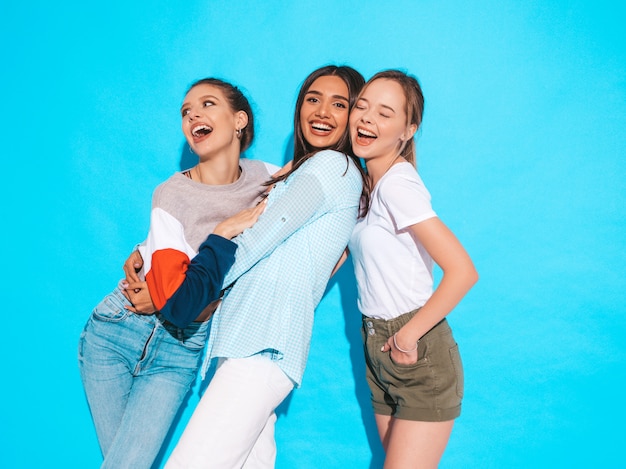 Sexy sorglose Frauen, die nahe blauer Wand im Studio aufwerfen. Positive Models, die Spaß haben und umarmen