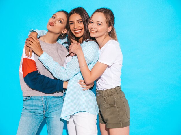 Sexy sorglose Frauen, die nahe blauer Wand im Studio aufwerfen. Positive Models, die Spaß haben und umarmen