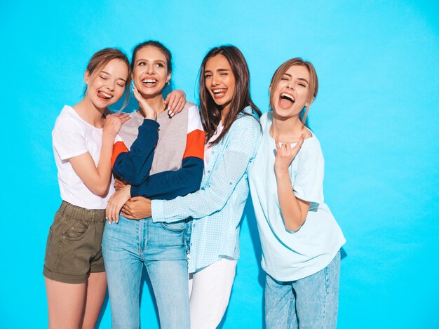 Sexy sorglose Frauen, die nahe blauer Wand im Studio aufwerfen. Positive Models, die Spaß haben und umarmen