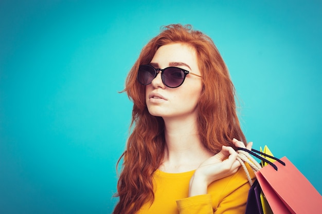 Shopping Concept - Close up Portrait junge schöne attraktive Redhair Mädchen lächelnd Blick auf Kamera mit Einkaufstasche. Blauer Pastellhintergrund. Platz kopieren