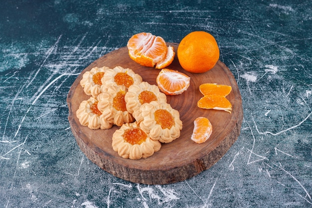 Shortbread mit Marmelade und geschälten Mandarinenfrüchten auf einer bunten Oberfläche.