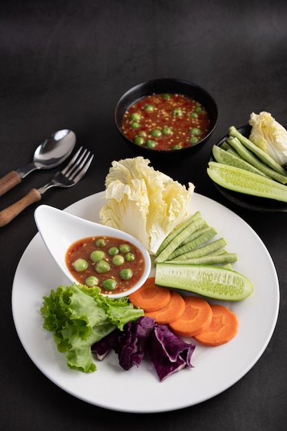 Shrimps-Paste-Sauce in einer Schüssel auf dem weißen Teller mit Gurke, Yard Long Bean, thailändischen Auberginen, gebratenem Weißkohl, Karotten und Salat