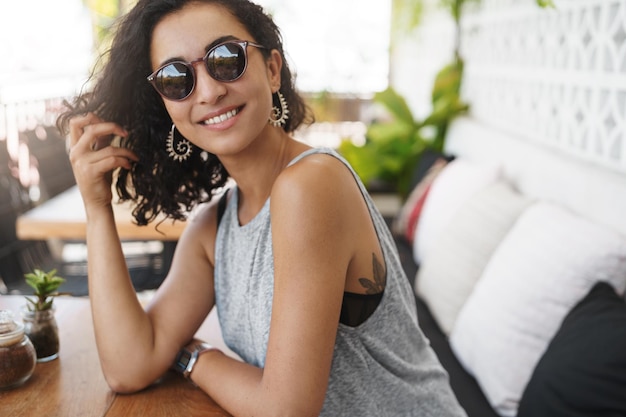 Kostenloses Foto sie sind ein glatter redner. attraktives flirty mädchen, das im café auf der terrasse im sommer sitzt