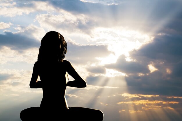 Silhouette der Frau praktizieren Yoga