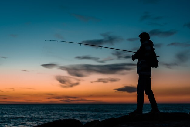 Silhouette der Person, die im Meer fischt