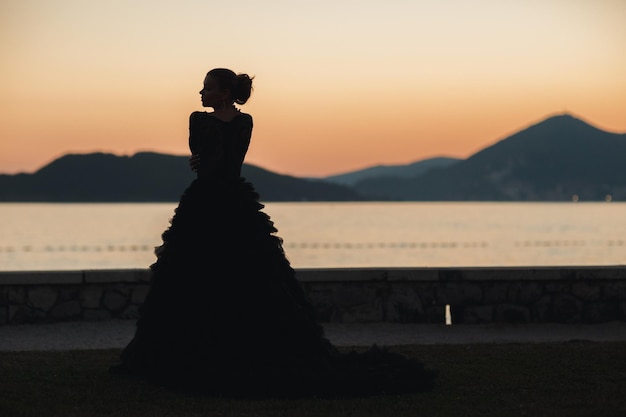 Kostenloses Foto silhouette einer frau in luxuriösem kleid in der nähe des meeres und der felsen