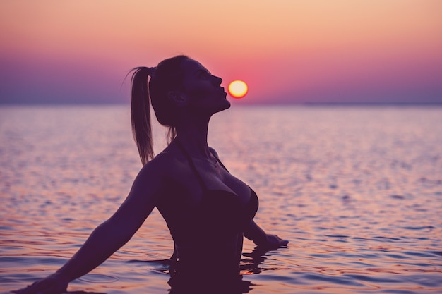 Silhouette einer jungen frau, die bei sonnenaufgang yoga am strand praktiziert Premium Fotos