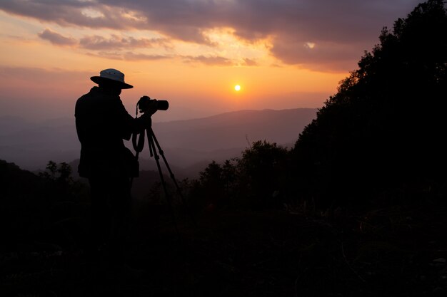 Silhouette eines Fotografen, der einen Sonnenuntergang in den Bergen schießt