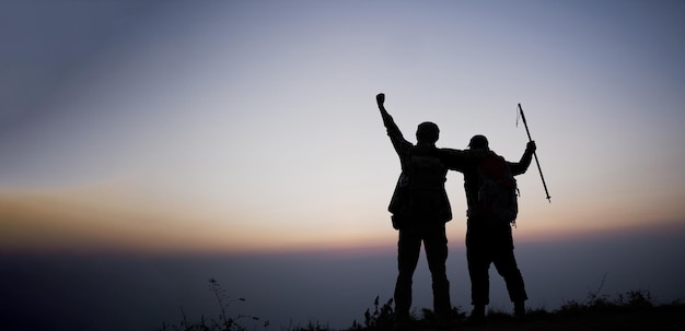 Silhouette von jubelnden Wandermännern öffnen die Arme zum Sonnenaufgang auf dem Berg Travel Lifestyle Fernweh Abenteuerkonzept Sommerferien im Freien