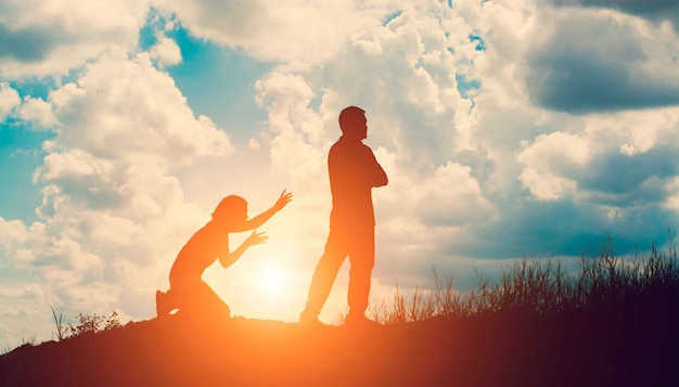 Silhouette von zorniger Mann mit seiner Frau kniend