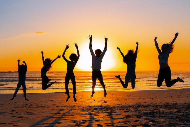 Kostenloses Foto silhouetten von menschen, die bei sonnenuntergang springen