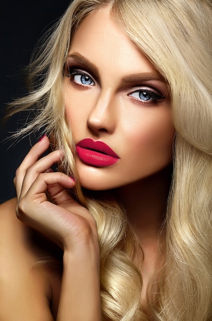 sinnliches Glamourporträt der schönen blonden Frau Model Lady mit hellem Make-up und rosa Lippen, mit gesundem lockigem Haar auf schwarzem Hintergrund