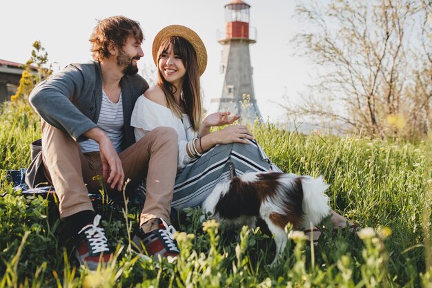 Sitzen im Gras junge stilvolle Hipster-Paar in der Liebe mit Hund in der Landschaft, Sommer-Stil Boho Mode, romantisch