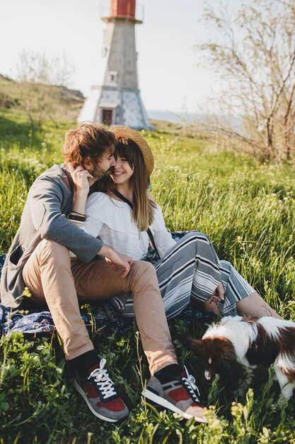 Sitzen im Gras junge stilvolle Hipster-Paar in der Liebe mit Hund in der Landschaft, Sommer-Stil Boho Mode, romantisch