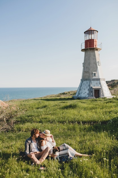 Sitzen im Gras junge stilvolle Hipster-Paar in der Liebe mit Hund in der Landschaft zu Fuß