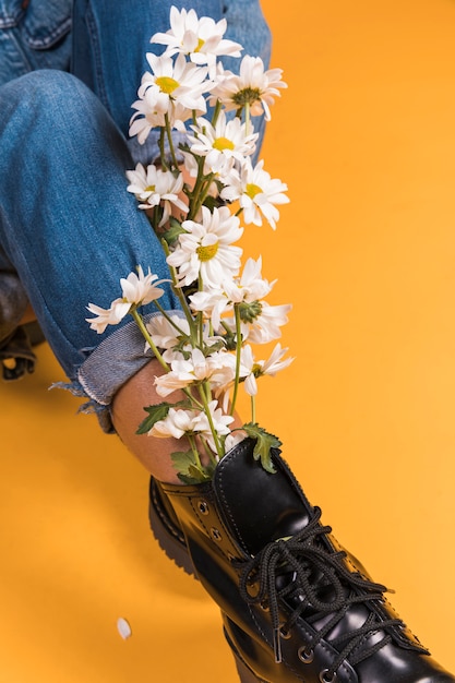 Sitzende Frauenbeine in Stiefeln mit Blumenstrauß nach innen