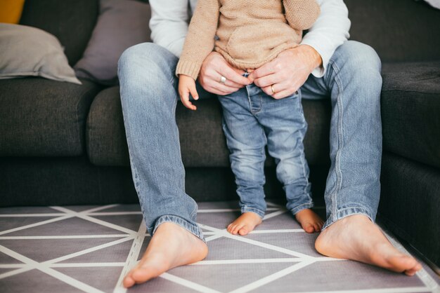 Sitzender Vater, der stehendes Kleinkind hält