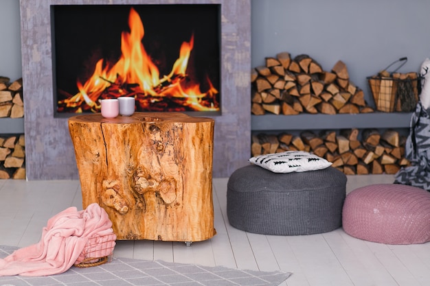 Skandinavisches interieur mit kamin, stumpftisch, holzhaufen für feuer