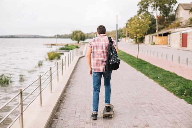 Skateboard des unerkennbaren Jugendlichreitens nahe Wasser