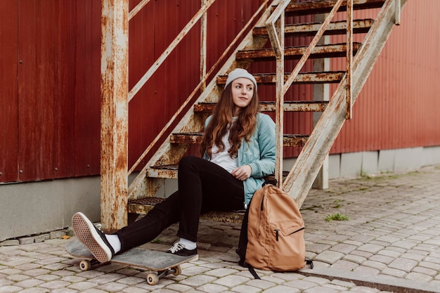 Skater-Mädchen in der Stadt, die auf der langen Ansicht der Treppe sitzt