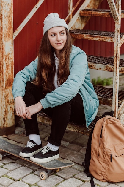 Skater-Mädchen in der Stadt, die auf Treppen sitzt