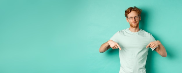 Kostenloses Foto skeptischer und gestörter mann mit rotem haar und bart, der eine brille und ein t-shirt-grinsen und eine punktflosse trägt